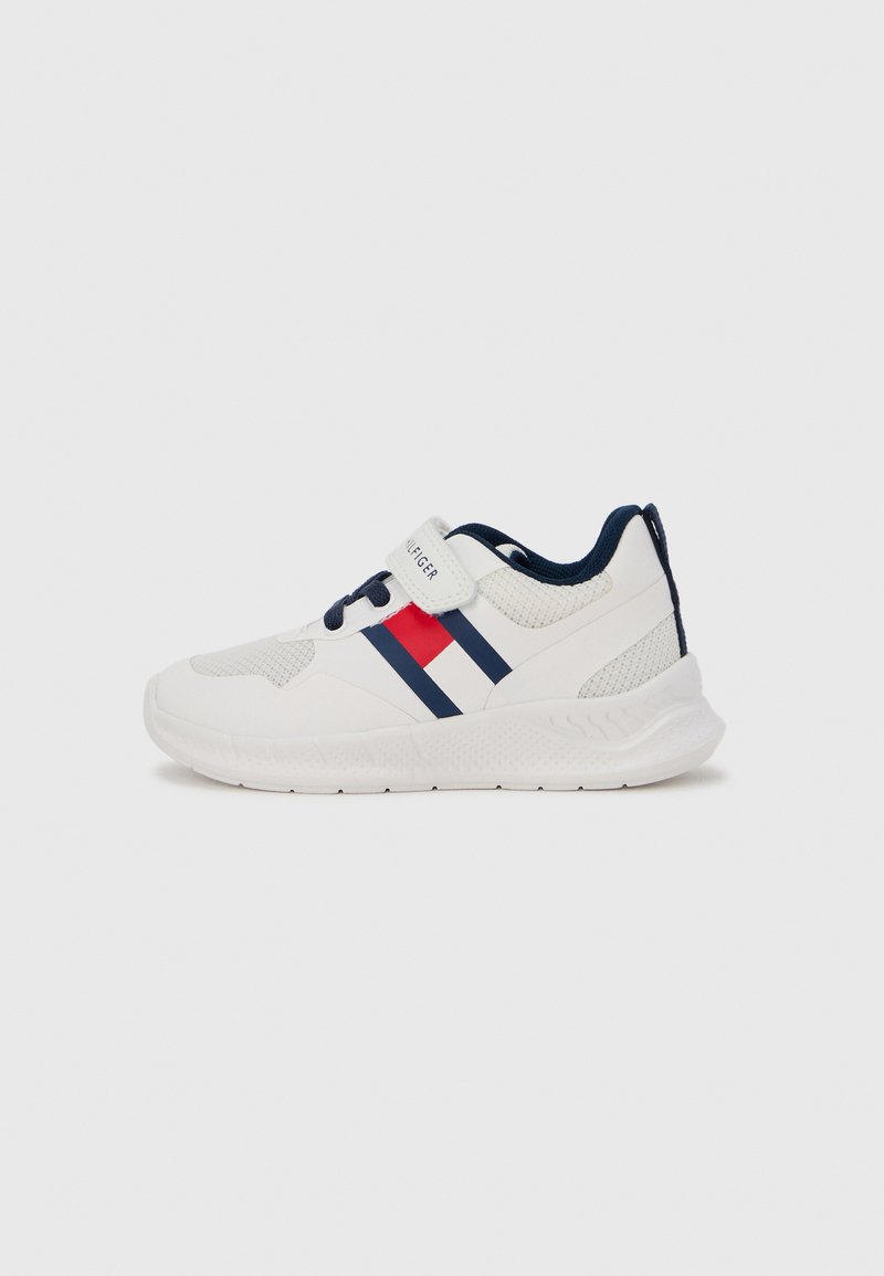 Chaussure de sport blanche avec accents bleu marine, tige en textile, fermeture par sangle et semelle en caoutchouc. Comprend deux bandes bleu marine et une rouge sur le côté.