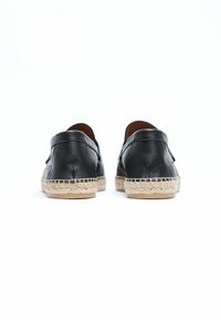 Zwarte leren espadrilles met gevlochten jute zolen, met een ronde achterkant, een gladde textuur en minimale stiksels langs de randen.