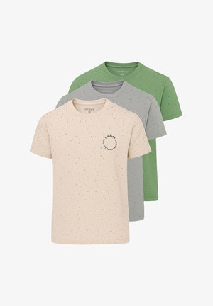 Lichtroze t-shirt met zwarte spettertjes en een klein logo op de borst, gecombineerd met zwarte cargoshorts en witte sneakers.
