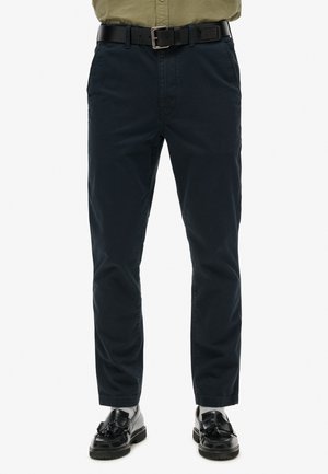 Pantalones ajustados azul marino oscuro con textura suave de algodón, que incluyen bolsillos laterales, cinturón y diseño de pierna cónica.