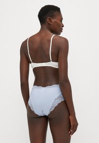 Soutien-gorge blanc avec des bordures en dentelle et culotte taille haute bleu clair. Le tissu est lisse, avec des accents en dentelle délicats le long des bords.