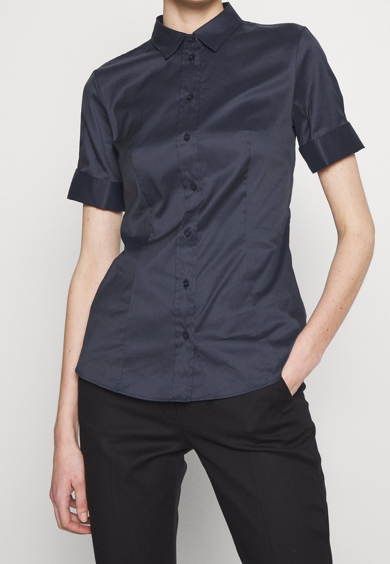 Mörkblå kortärmad skjorta med knappar, klassisk krage, slät yta och vikta ärmslut, figursydd design och svarta knappar.
