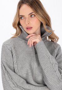 Pulover gri cu fermoar, cu modele texturate, având un guler înalt și manșete strâmte. Material moale cu accente tricotate în tip cablu pe mâneci.