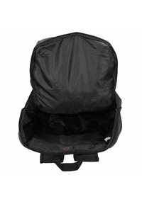 Mochila negra con cierre de cremallera. El interior es amplio, con una textura suave y mate sin compartimentos. Se ve un hardware mínimo.