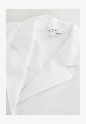 Valkoinen bleiseri, jossa on lovettu kaulus, sileä tekstuuri ja näkyvissä oleva "NEXT"-labeli. Bleiserissa on räätälöidyt kaulukset ja siisti muotoilu.