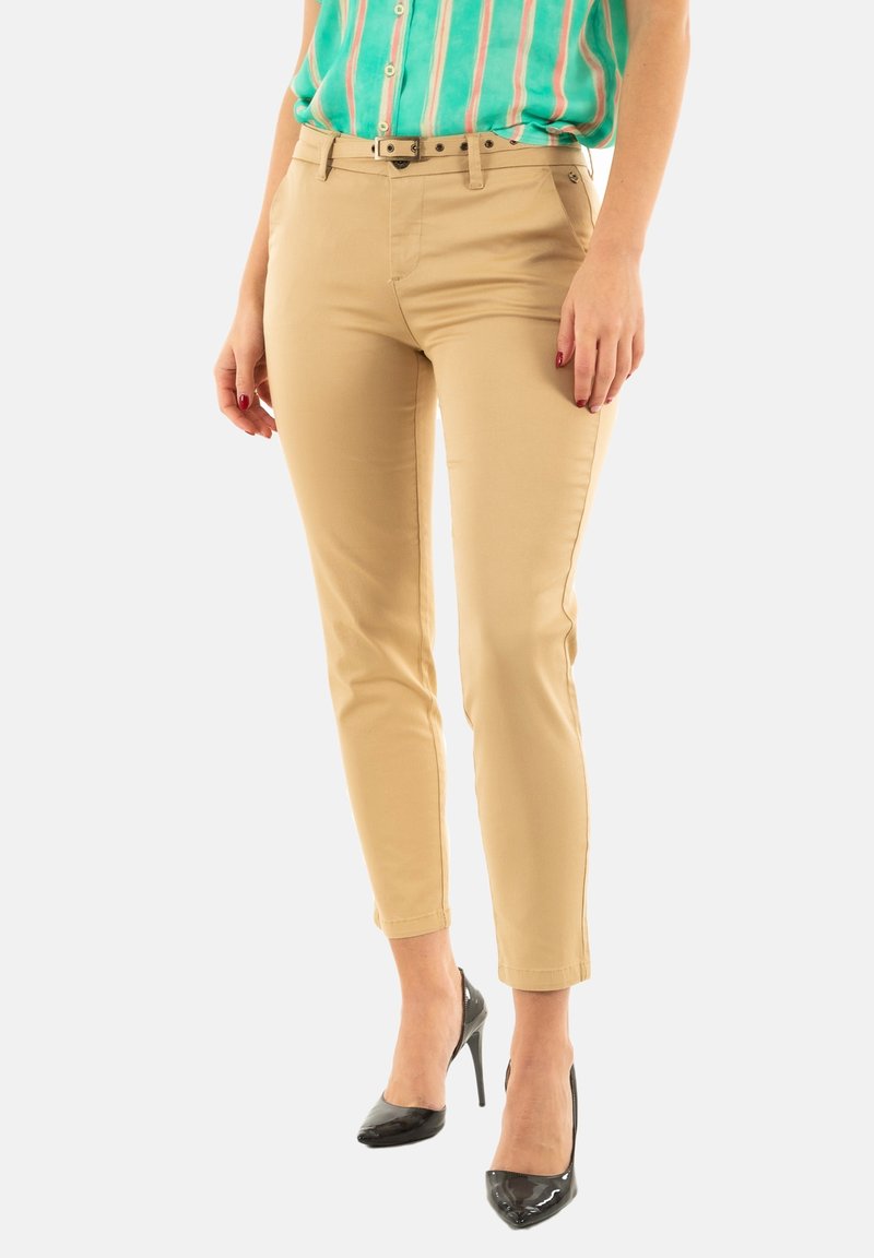 Chinos beige con un corte ajustado, que cuentan con una cintura de media altura, trabillas para el cinturón y bolsillos laterales. Combinados con una camisa de rayas colorida y tacones negros.