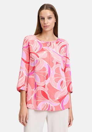 Leichtes, pinkes Blusenshirt mit floralen Mustern in verschiedenen Rosatönen und Lila. Mit Rundhalsausschnitt und dreiviertellangen Ärmeln mit gerafften Bündchen.