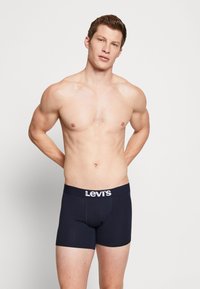 Marineblauwe boxershorts met een zachte elastische tailleband met een wit "Levi's" logo. De stof lijkt glad en aansluitend.