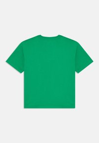 T-shirt de algodão verde com decote redondo e mangas curtas. Design simples, cor sólida e um ajuste relaxado sem adornos.