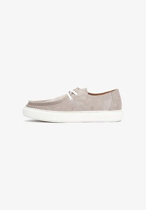 Zapato casual de ante beige con cordones blancos y suela gruesa de goma blanca, diseño de corte bajo y costura estilo mocasín a lo largo de la punta.