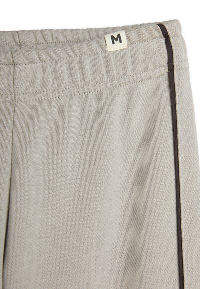 Light grey sweatpants with a textured fabric, featuring a gathered waistband and a dark brown side stripe. Size label 'M' visible.