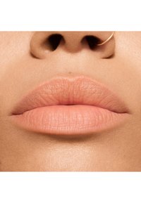 Gros plan sur des lèvres lisses de couleur rose clair avec une finition naturelle, sur un fond de teint neutre ; comprend un petit anneau de nez doré fin.