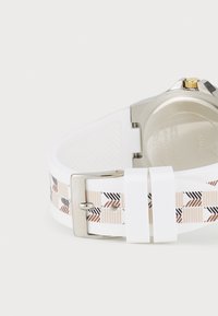 Bracelet de montre blanc avec un motif géométrique noir et rose doré, doté d'une boucle en métal argenté et d'un fond en acier inoxydable.