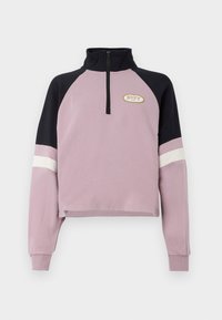 Fialový skrátený pulóver s čiernym golierom a akcentmi na rukávoch. Obsahuje polovičný zips a zlaté logo Roxy na hrudi. Mäkká textúra.