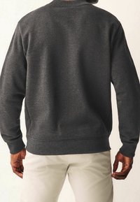 Tmavě šedá mikina s žebrovaným kulatým výstřihem a manžetami, s hladkou texturou a volným střihem, bez viditelných log nebo vzorů.