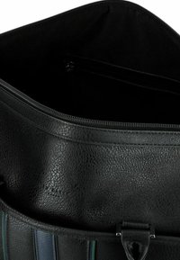 Schwarzes, strukturiertes Leder-Innenfach mit Reißverschluss; verfügt über ein glattes Stofffutter und eine Innentasche zur besseren Organisation.