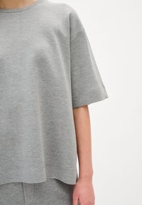 Grijze korte mouwen t-shirt gemaakt van zachte, niet-geweven stof. Kenmerkt zich door een losse pasvorm en een ronde zoom, met minimale stikdetails.