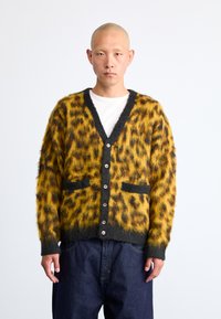 Κίτρινο και μαύρο καρντιγκάν με σχέδιο λεοπάρ, κλείσιμο με κουμπί, v-neck και δύο μπροστινές τσέπες. Μαλακή, αφράτη υφή, αντίθετες μαύρες άκρες.