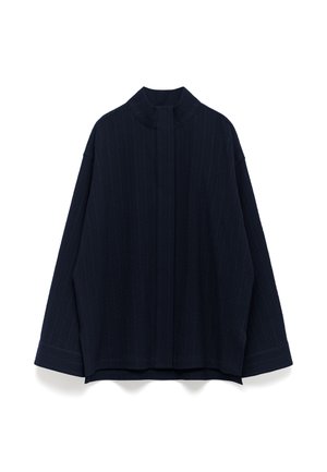 Top oversized navy in tessuto testurizzato, con colletto alto, spalle scese e maniche larghe con polsini a contrasto.