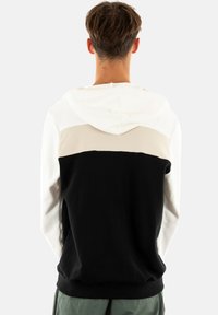 Felpa con cappuccio caratterizzata da un design a blocchi di colore con sezioni bianche, beige e nere. Realizzata in tessuto morbido con una vestibilità standard e orlo.