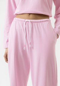 Lichtroze katoenen sweatpants hebben een elastische tailleband, een trekkoord met roze uiteinden en zijzakken. Zachte textuur, casual pasvorm.