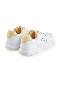 Witte sneakers met gele accenten, geperforeerde details, platte zool en vetersluiting. Bevat logo aan de zijkant en een gewatteerde kraag.
