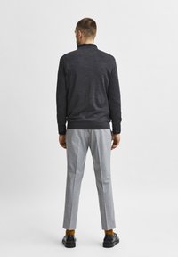 Dark gray long-sleeve sweater with a collar, paired with light gray tailored pants and black shoes, featuring mustard-colored socks.