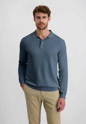 Blue ribbed long-sleeve polo with a collar and button placket, paired with beige pants, showcasing a textured fabric and fitted design.