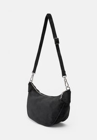Borsa a spalla nera in suede dalla forma curva, con accessori in argento, tracolla regolabile e chiusura con zip nella parte superiore.