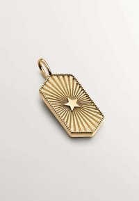 Colgante de oro con forma hexagonal, adornado con líneas radiales y un detalle central en forma de estrella. Textura suave con un borde intrincado.