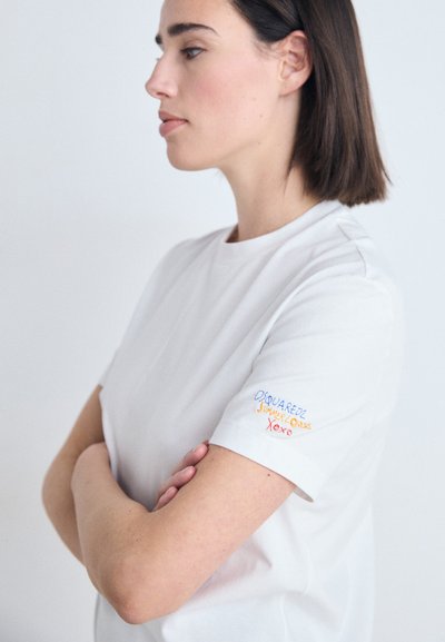 White cotton t-shirt with a relaxed fit, featuring embroidered text in blue, orange, and red on the left sleeve. Crew neckline, short sleeves.
