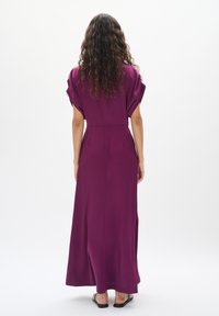 Robe longue fluide et lavande avec des manches courtes bouffantes, taille cintrée et texture lisse. Design minimaliste avec une couture arrière droite.