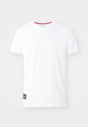 Camiseta de algodón blanca con escote redondo, que presenta un acento rojo en el interior del cuello y una pequeña etiqueta negra en la parte inferior izquierda.