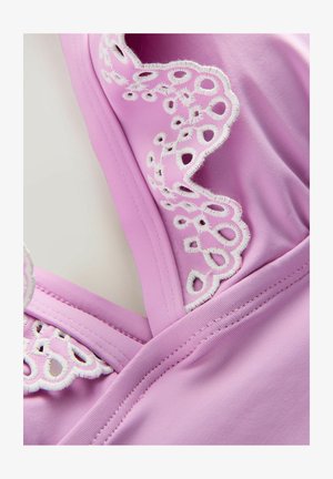 Roze stof met een gladde textuur heeft ingewikkelde witte kantdetails langs de halslijn en schouderbanden, wat de ontwerpelementen benadrukt.