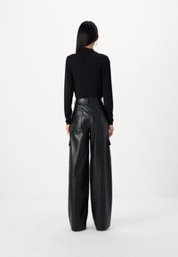 Black long-sleeve top and high-waisted, wide-leg leather pants with cargo pockets. Smooth texture and tailored fit.