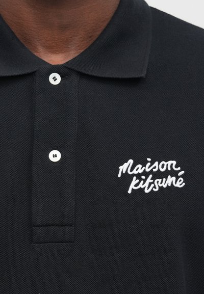 Čierna polo košeľa z textúrovaného materiálu, s troj-gombíkovým zapínaním a bielym vyšitým logom "maison kitsuné" na hrudi.