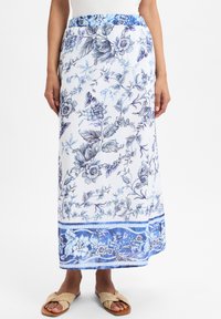 Maxi-jurk met bloemenprint in blauw en wit, met een smockband aan de taille en een gedetailleerd randpatroon in verschillende blauwtinten.