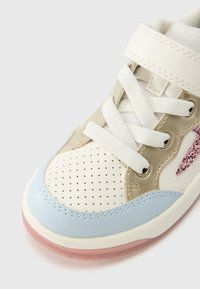 Baskets avec une palette de couleurs crème et bleu clair, matériaux en suède et synthétiques, bout perforé, lacets blancs et semelle translucide rose.