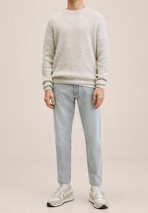 Světlounce šedý svetr z pletené textury, světle modré zúžené džíny a bílé tenisky s béžovými detaily. Jednoduchý a ležérní design.