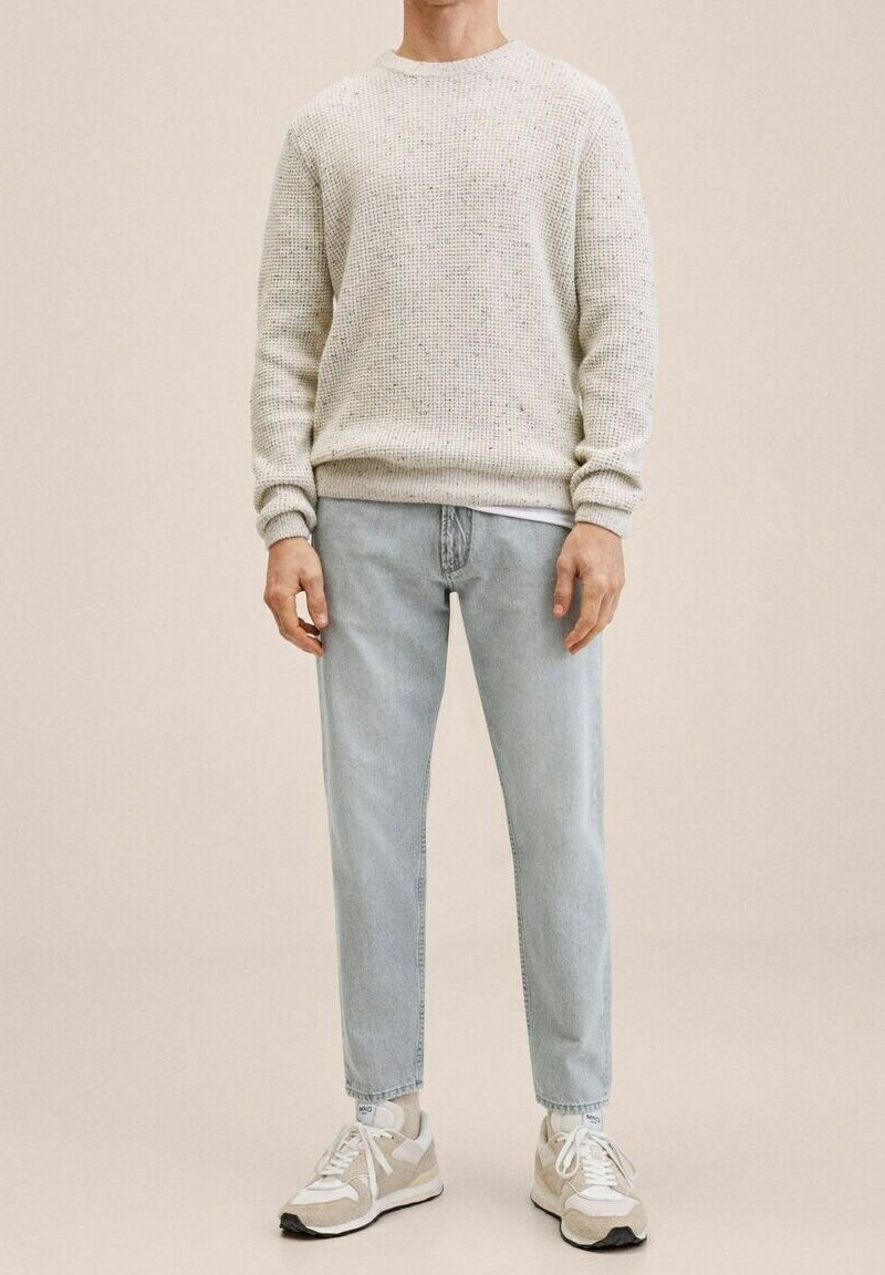Světlounce šedý svetr z pletené textury, světle modré zúžené džíny a bílé tenisky s béžovými detaily. Jednoduchý a ležérní design.