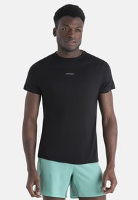Camiseta negra de manga corta con cuello redondo y sutil logo "icebreaker" en el centro, hecha de un material suave y ligero.