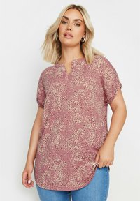 Blusa a maniche corte con scollo a V in malva, caratterizzata da un motivo floreale con accenti crema. Tessuto leggero e testurizzato, orlo arrotondato.