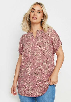 Blusa de manga corta y cuello en V en color malva, con un patrón floral y acentos en crema. Tejido ligero y texturizado, con dobladillo redondeado.