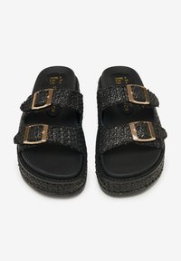 Infradito neri a slip-on realizzati in materiale testurizzato con due ampie cinghie, decorate con accenti di fibbia dorata e una suola piatta imbottita.