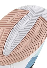 Semelle d'une basket présentant du caoutchouc rose clair, blanc et bleu avec un motif texturé et des rainures pour l'adhérence.