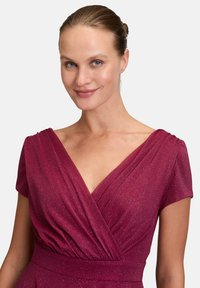 Bordeauxfarbiges drapiertes Kleid mit kurzen Ärmeln, das eine schimmernde Textur und einen tiefen V-Ausschnitt aufweist. Elegante Falten an den Schultern und der Taille.