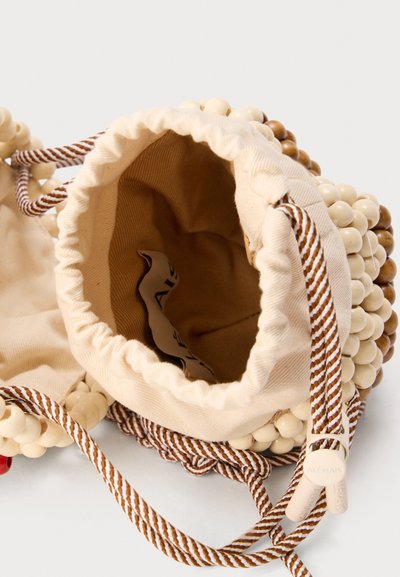 Μικρό μπεζ πουγκί με κορδόνι που δένεται, με ξύλινη χάντρα εξωτερικά και καφέ-λευκές ριγέ κορδόνια, εμφανιζόμενο ανοιχτό με ορατό ύφασμα στο εσωτερικό.