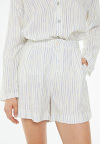 Lightweight striped shorts in white and blue, featuring a relaxed fit, pleats, and side pockets. The fabric has a slightly textured finish.