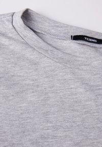 Šedé bavlněné tričko s kulatým výstřihem, s hladkou texturou a jemným melírovaným vzorem. Štítek nese nápis "TEZENIS."