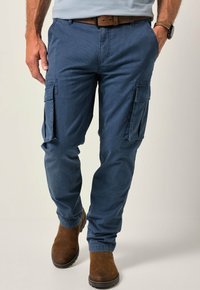 Modré cargo kalhoty vyrobené z texturované látky, s vícero bočními kapsami a zúženým střihem, v kombinaci s hnědými koženými botami.